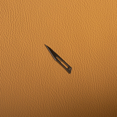 metal scalpel blade on a brown leather background