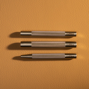 Three metal rivet setters with the craftplus logo visible. Laid out on a brown textured leather background.
