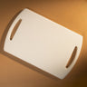 White cutting board with handles on a brown background