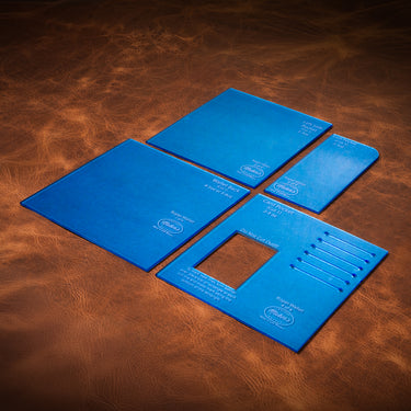 A set of blue maker's leather supply acrylic templates for leatherworking laid out on a textured brown leather background.