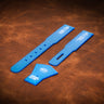 A set of acrylic blue templates used for creating a custom pair of suspenders out of leather. Laid out on a textured brown leather background.