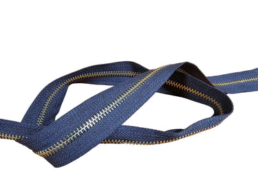 A Yard of YKK brand zipper, brass and black in color, displayed on a white surface.
