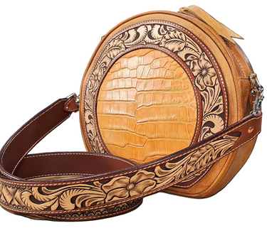 A tooled leather canteen purse with floral patterns and a round shape, featuring a shoulder strap.