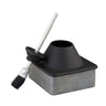 Black and gray ceramic glue pot for storing glues and adhesives, sitting along side a brush used to seal the container. Laid out on a white background.