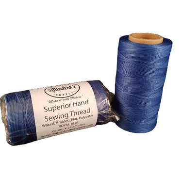 Two spools of royal blue hand sewing thread, one standing upright and the other lying horizontally, with packaging that includes the brand name and thread details.