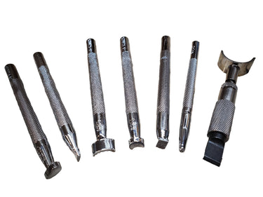 A collection of leather stamping tools laid out on a white background, patterns include cross-hatching, seashells, stippling and crescent shapes.
