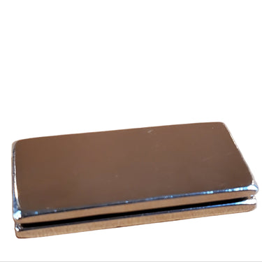 A rectangular metal money clip magnet placed on a surface with a white background.