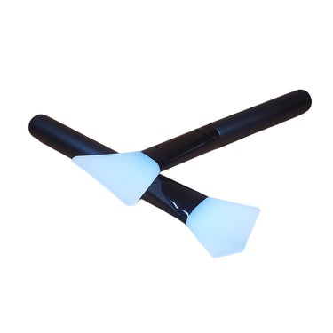 Two black glue spreaders with white silicon tips placed on a surface with a leather maker's supply logo.