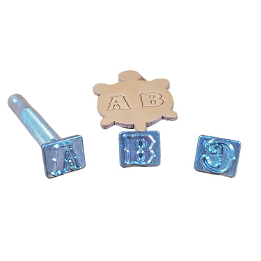 A collection of aluminum letter stamps for leather crafting, arranged in a line with a handle, against a white background.