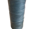 A spool of teal-colored hand sewing thread placed on a white surface.