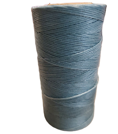 A spool of teal-colored hand sewing thread placed on a white surface.