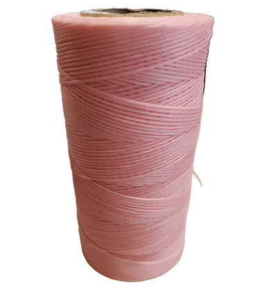 A spool of pink hand sewing thread on a white background.