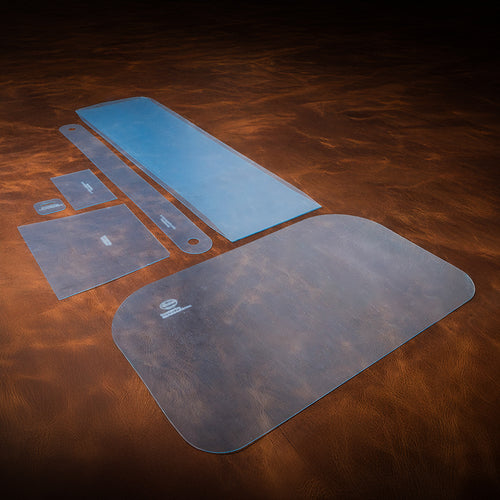 A set of blue acrylic templates used for creating a custom leather overnight bag. Laid out on a brown textured leather background. 