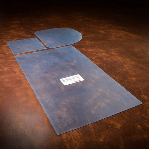 A set of blue acrylic templates used for creating a custom duffle bag out of leather, laid out on a textured brown leather background. 