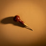 A stitching awl used for creating stitch holes on leather textiles, including a metal tip and wooden handle branded with the maker's leather supply logo, laid out on a light brown textured leather background. 