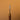 A paint roller tool with a textured metal tip and sturdy wooden handle, used for applying paint to leather surfaces, laid out on a solid light brown background. 