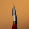 A `bleeder' tool, used for leather crafting and tooling. Laid out on a solid brown background. 