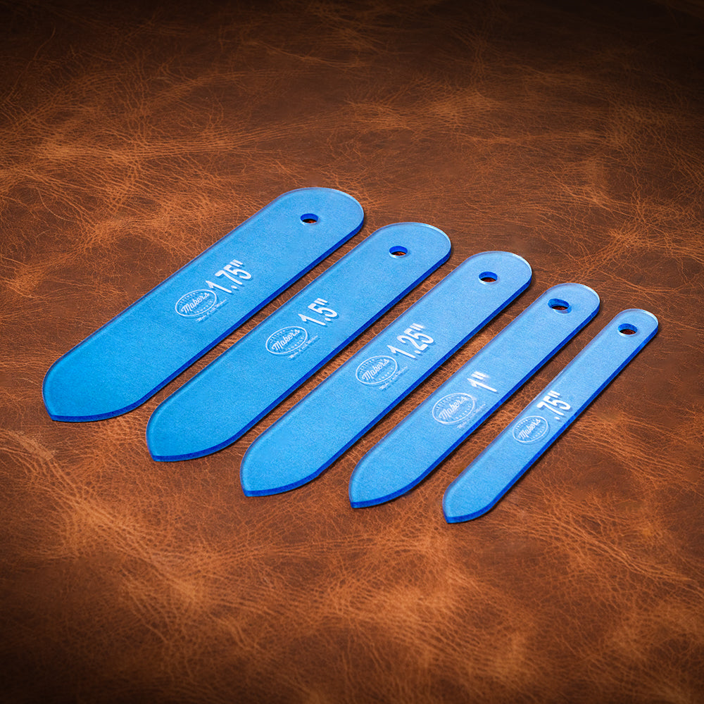 A set of blue acrylic templates used for creating custom belt ends made from leather. Laid out on a textured brown leather background. 