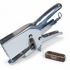heavy duty stapler next to a leather band on a white background. 