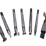 A collection of leather stamping tools laid out on a white background, patterns include cross-hatching, seashells, stippling and crescent shapes.