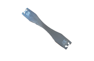 A zipper tooth remover tool lying on a white surface.