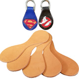 A set of beige double-sided key fob blanks displayed on a dark fabric, alongside two finished key fobs with colorful character logos.