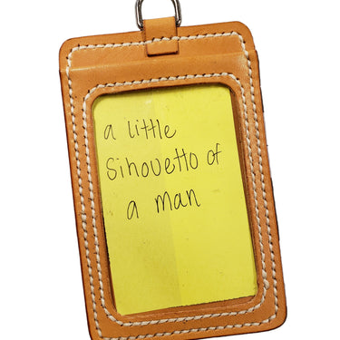 A leather ID badge holder with a clear plastic window on the front and two card slots on the back, displayed on a white background.