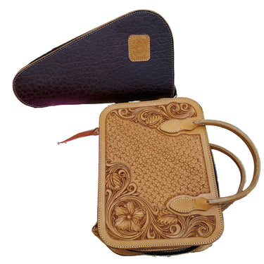 A set of two pistol cases, one rectangular and one triangular, displayed on a table. The rectangular case is adorned with tooling patterns, and both cases are made from a brown leather.